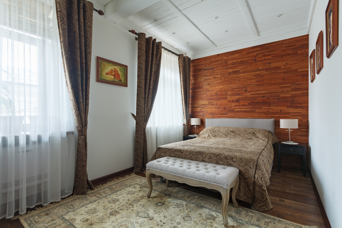 Стена за изголовьем кровати облицована деревянными панелями производства Admonder.